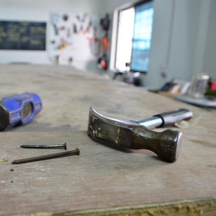 ToolsA claw hammer resting on a table next to nails.