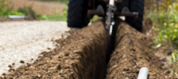 A trencher digging into the ground.