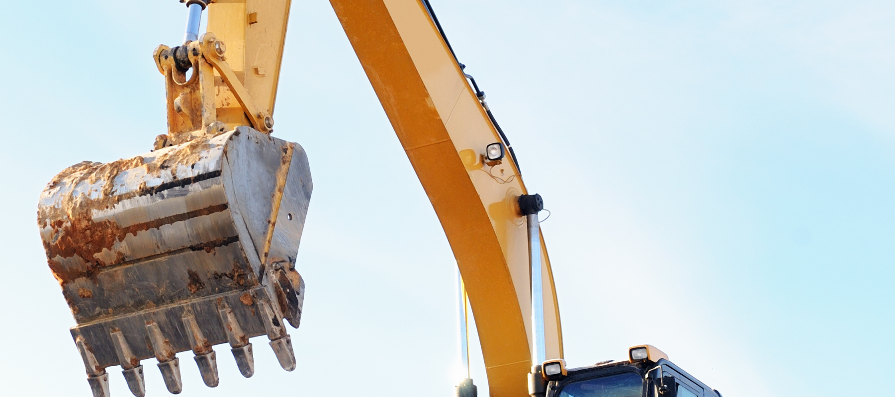 An excavator posed outdoors on a clear day.